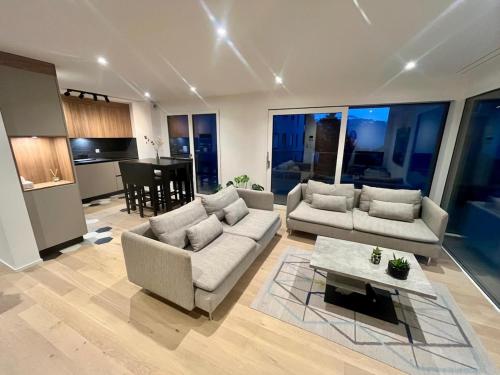 a living room with two couches and a table at Newly built 2-Bed Flat with parking in Pully in Pully