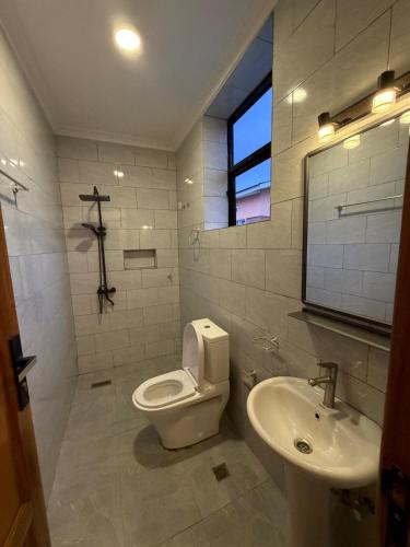 Un baño blanco con inodoro y lavabo. en CityGlow Apartment, en Kigali