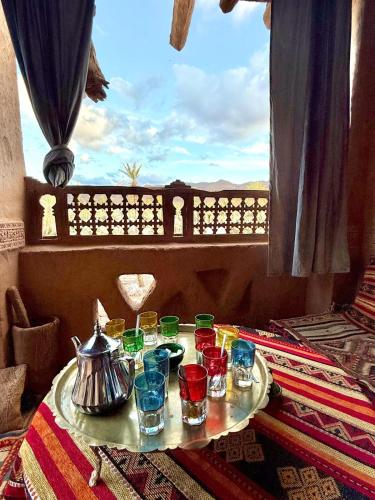 a table with cups and a tea pot on a table with a window at Kasbah Maktob Tamnougalt in Agdz