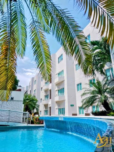 a swimming pool in front of a building with palm trees at Angeles Suites & Hotel in Veracruz
