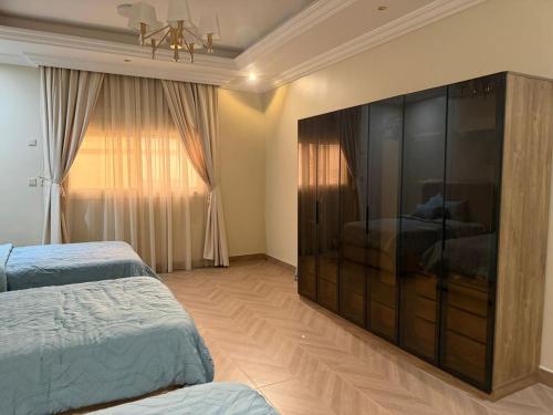 a bedroom with two beds and a large entertainment center at رحاب قريش in Al Masfalah