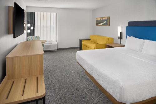 a hotel room with a bed and a yellow chair at Hampton Inn Chicago-Carol Stream in Carol Stream