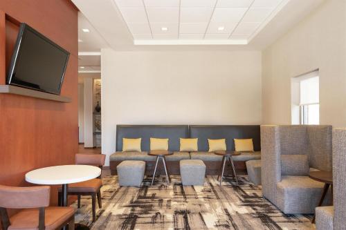 a waiting room with a couch and chairs and a tv at Hampton Inn Portland Downtown Waterfront in Portland
