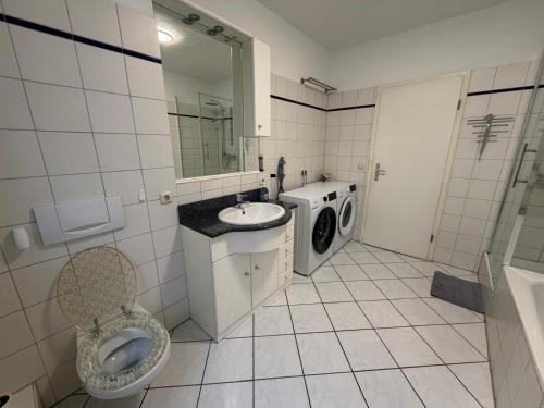 a bathroom with a toilet sink and a washing machine at Home4You Hamburg-Neugraben EG in Hamburg
