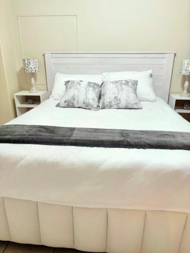 a large white bed with two pillows on it at Durban Oceanic Apartment 117 in Durban