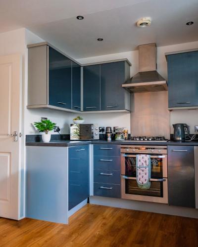 a kitchen with blue cabinets and an oven at Luxury Penthouse Balcony Flat - 5 Min to Canary Wharf - Prime Long Stays in London