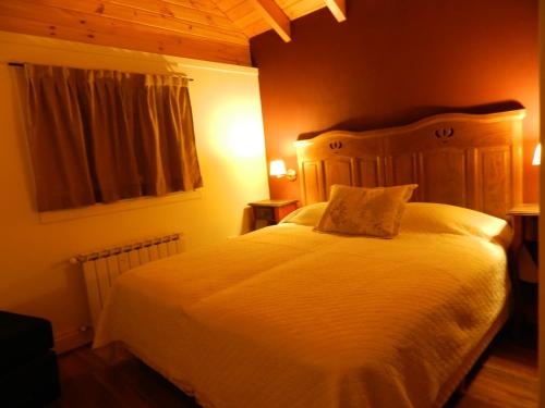 Un dormitorio con una cama blanca con cabecero de madera. en Ayelen Cabañas, en Villa La Angostura