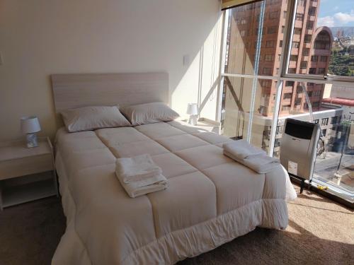 a large bed in a room with a large window at Departamento de lujo 2D Av Arce in La Paz