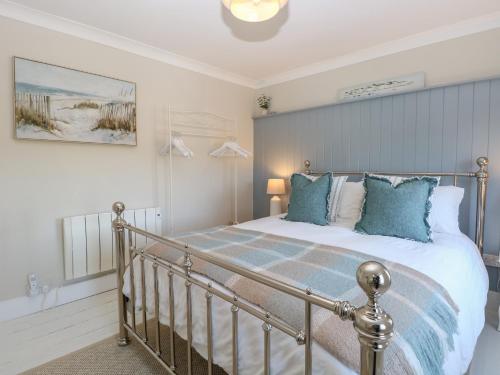a bedroom with a large bed with blue pillows at Herbies Cottage in Snettisham