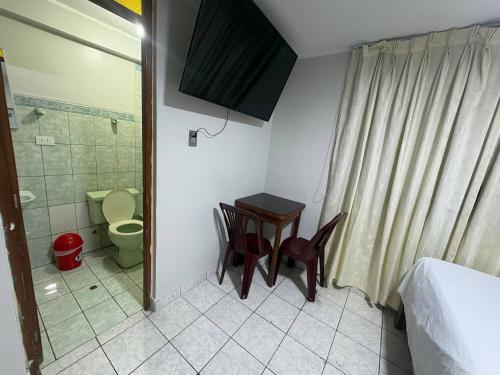 a small bathroom with a toilet and a table and chairs at Hospedaje W TAWA in Lima