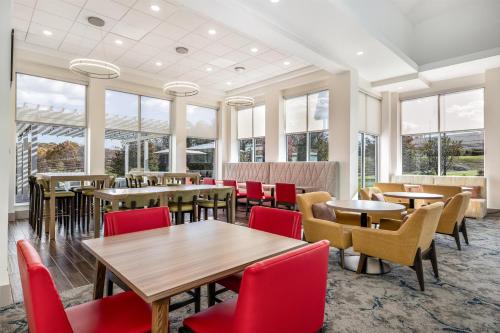a restaurant with tables and chairs and windows at Hilton Garden Inn Mystic/Groton in Groton
