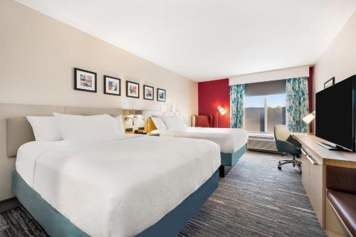 a hotel room with two beds and a flat screen tv at Hilton Garden Inn Mystic/Groton in Groton