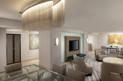 a living room with a couch and chairs and a television at Hilton Los Angeles Airport in Los Angeles