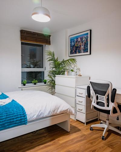 a bedroom with a bed and a desk and a chair at Luxury Penthouse Balcony Flat - 5 Min to Canary Wharf - Prime Long Stays in London