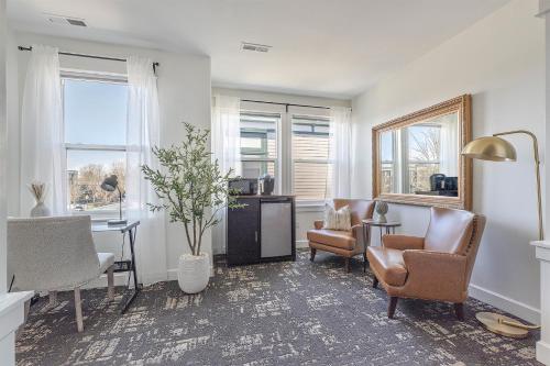 a living room with chairs and a table and windows at The Orenco Station Hotel in Hillsboro