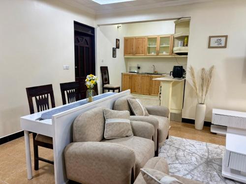 a living room with a couch and chairs and a kitchen at Jefes Haven in Dar es Salaam