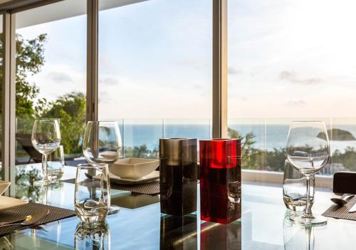 a glass table with wine glasses on top of it at The Seaview Kata in Kata Beach