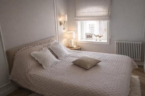 a white bed with two pillows and a window at Oficyna Drukarza in Wschowa
