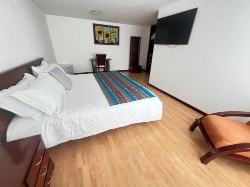 a bedroom with a large bed and a flat screen tv at Nogal Suite Hotel Pasto in Pasto