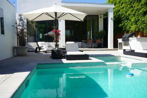 a swimming pool with an umbrella and chairs and a table at The Hollywood House in Los Angeles
