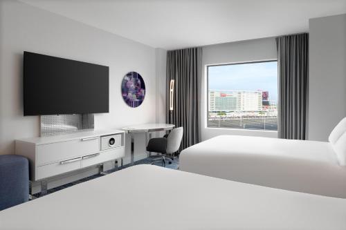 a hotel room with two beds and a desk with a tv at Hilton Santa Clara - Newly Renovated in Santa Clara