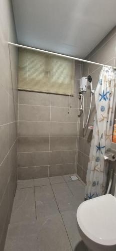 a bathroom with a toilet and a shower curtain at D'Millenia Residences Steady in Kota Samarahan