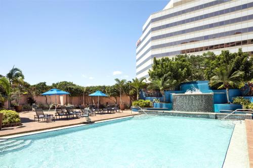 a swimming pool with tables and chairs and a building at Embassy Suites by Hilton Tampa Airport Westshore in Tampa