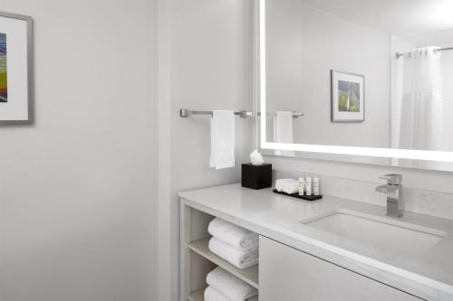 a white bathroom with a sink and a mirror at Embassy Suites by Hilton Tampa Airport Westshore in Tampa