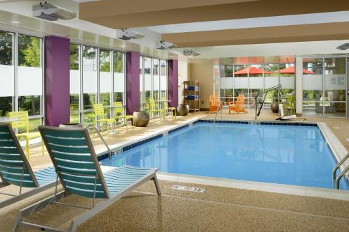 a pool in a hotel room with chairs and tables at Home2 Suites by Hilton Arundel Mills BWI Airport in Hanover