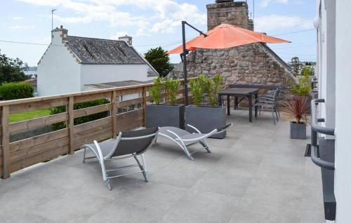 a patio with chairs and a table and an umbrella at Kerarmoor in Plouhinec