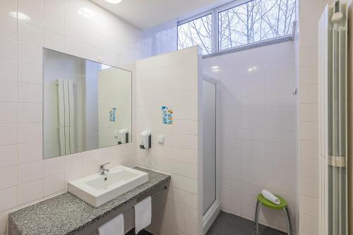 a white bathroom with a sink and a mirror at HI Lousã – Pousada de Juventude in Lousã