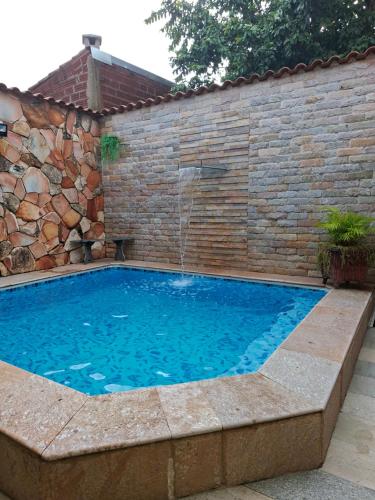 a swimming pool with a waterfall in a brick wall at Cantinho Abençoado in Pirenópolis