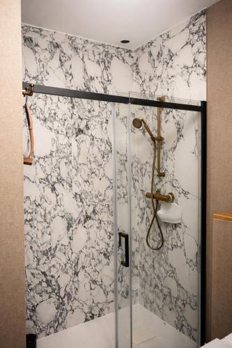 a shower with a glass door in a bathroom at Oficyna Drukarza in Wschowa