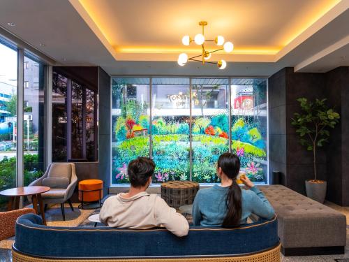 two people sitting in a room looking at a large window at Tokyu Stay Nishi Shinjuku in Tokyo