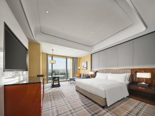 a hotel room with a bed and a flat screen tv at Hilton Fuzhou in Fuzhou