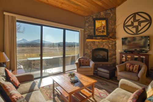 a living room with a fireplace and a large window at Lodge Condo 001 in Black Butte Ranch
