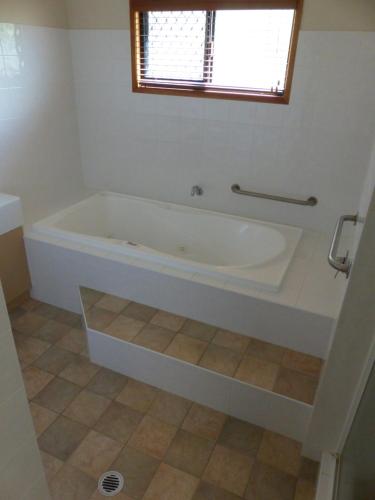 a white bath tub in a bathroom with a window at Alstan 3 Bedroom Beach House in Coolum Beach