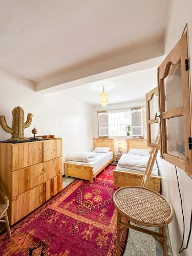 a bedroom with two beds and a table and a chair at Surf and Stay Anza - Surf Territory in Agadir