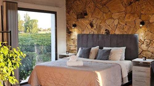a bedroom with a large bed with a stone wall at Rincon del Malbec in Ciudad Lujan de Cuyo