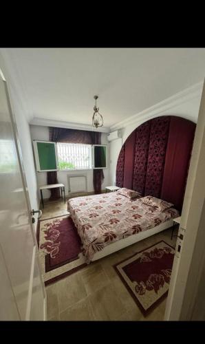 a bedroom with a large bed and a window at Appartement rez de jardin in Hammamet