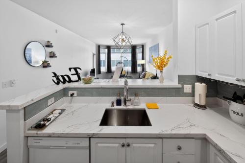 a white kitchen with a sink and a mirror at Vibrant City Gem/99 Walk/Pike Pl/Pool/Pet/Parking in Seattle