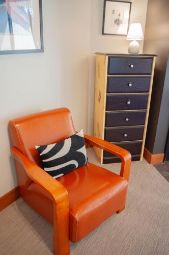 an orange chair with a pillow in front of a dresser at Lodge Room 015 in Black Butte Ranch