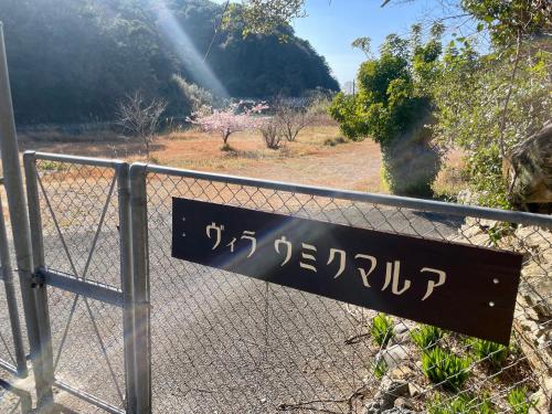 a sign on a fence in front of a road at ビーチ付きのプライベートスペースで海水浴して焚き火やバーベキューが楽しめる1日1組貸切宿 in Otsuki