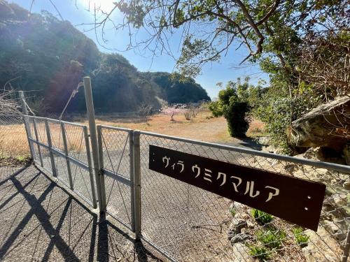 a sign on a fence next to a road at ビーチ付きのプライベートスペースで海水浴して焚き火やバーベキューが楽しめる1日1組貸切宿 in Otsuki