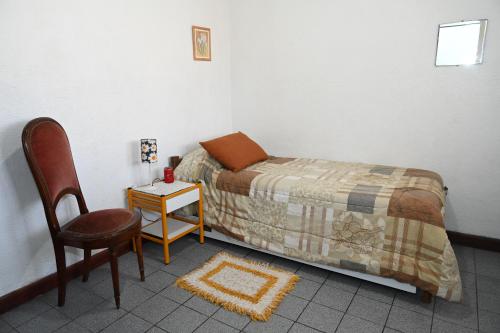 a bedroom with a bed and a chair and a table at Como en casa in Rawson