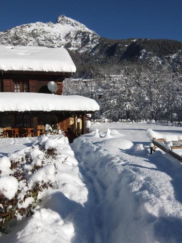 a house covered in snow next to a mountain at La Luge D'Antan Maison d'Hôtes & SPA in Brusson