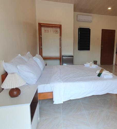 a bedroom with a large white bed with a lamp at Secret Garden Inn in Tagum