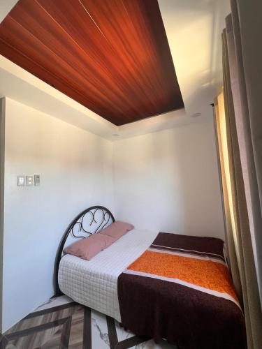 a small bedroom with a bed with a wooden ceiling at JO's HOMEtel SL 1 in Sampong