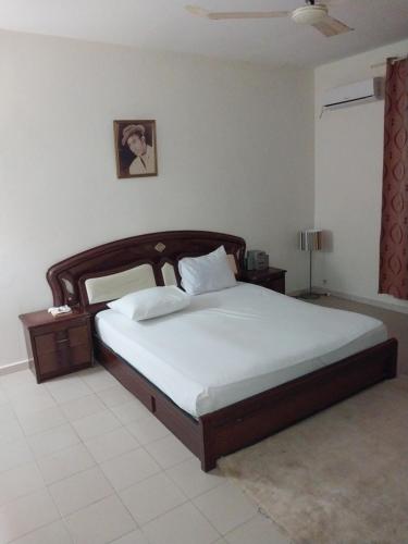 a bedroom with a large bed with a wooden headboard at Keur Fall Aéroport in Saint-Louis