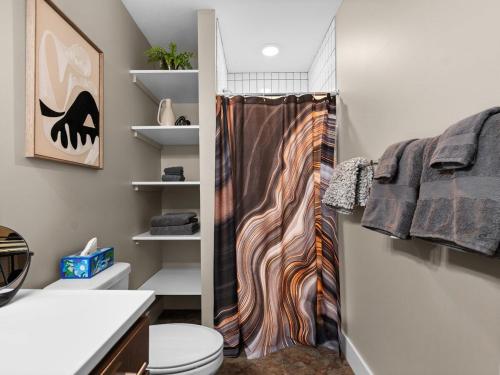 a bathroom with a shower curtain and a toilet at TC Parkside G: Spacious 2BR Condo in Traverse City